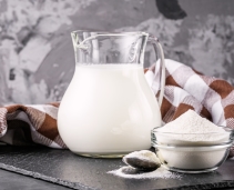 Instant skimmed milk powder next to a jug of milk
