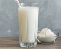 Regular full cream milk powde next to a glass of milk